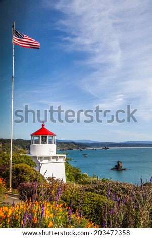 Memorial Lighthouse in Trinidad California, colorful flowers view and colorful bay and the USA flag