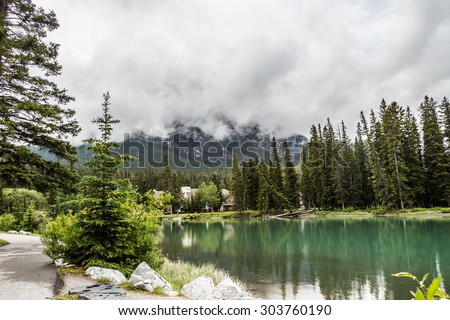 Path near the Bow River in Banff with rain clouds covering the summit. The Canadian Rockies have numerous high peaks and ranges. The Canadian Rockies are composed of shale and limestone