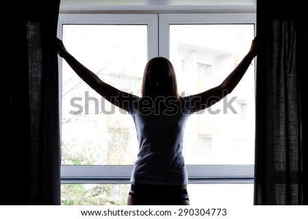 Silhouette of a young woman near the window in the morning