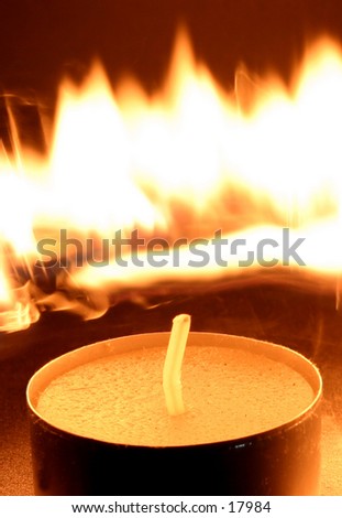 An unlit candle with flames behind.  Could be used to display the theme of waiting for your moment.  