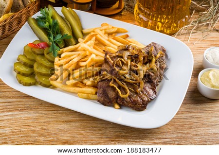 Roast beef, french fries and jug of beer on the rural table