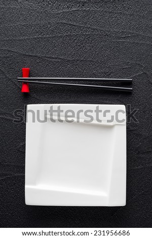 Chopsticks and white plate on black rock