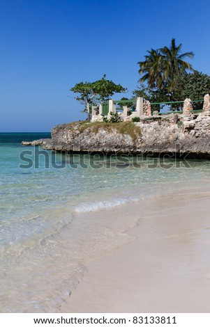 Beach in Cuba with white sand, transparent clean turquoise water and palmtrees against blue sky.