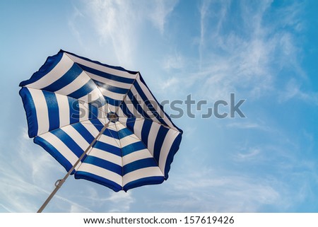 Striped sun umbrella under brightly shining sun