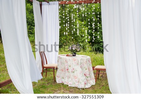 Outdoor gazebo with white curtains. Wedding decorations. Art object.