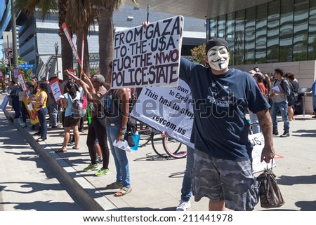 A man stands with a Guy Fawkes mask on outside of LAPD Headquarters in Downtown Los Angeles protesting the killing of Ezell Ford on August 17, 2014