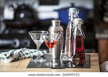 Cocktails and supplies on a bar counter in front of a stove.