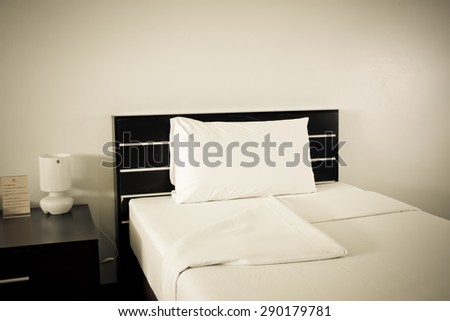 Still life of an empty bed in a hotel bedroom with soft cushions vintage