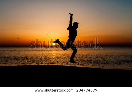 Silhouette of jumping man on sunrise background