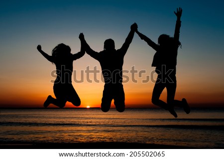 silhouette of friends jumping on beach during sunrise time