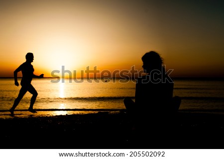 Silhouette young woman practicing yoga on the beach at sunrise and an old man running on the beach