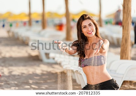 Happy sunshine woman. Girl smiling friendly looking at camera on sunny summer day under the hot sun on beach playing with sand.