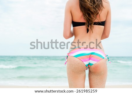 Sexy sandy woman buttocks on tropical beach background near ocean
