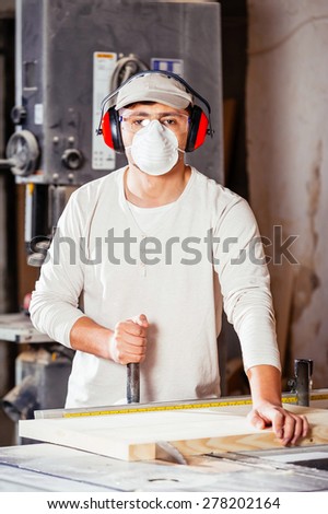 Carpenter working  cutting some boards, he is wearing safety glasses and hearing protection