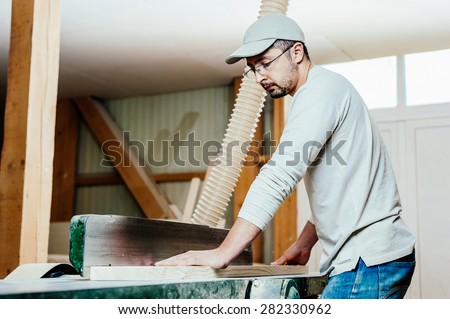 Carpenter working on wood machine in factory