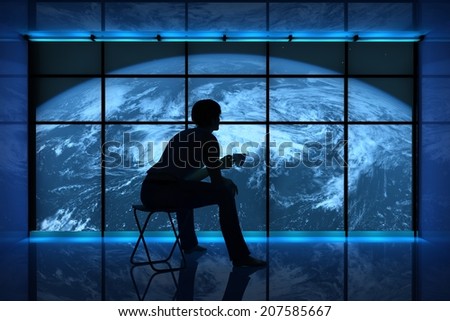 Silhouette of a man with a cup on the background of the planet.