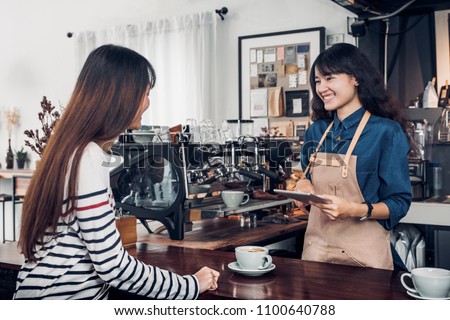 Asia Barista waiter take order from customer in coffee shop,cafe owner writing drink order at counter bar,Food and drink business concept,Service mind concept