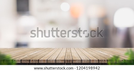 Empty brown wooden plank table top with blurred home kitchen with blur foreground leaf,Mock up template for display or montage of your design,Banner for advertise of product,panorama view