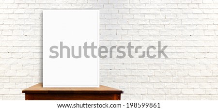 White frame mock up on the wood table at long white brick wall,leave space to add text content