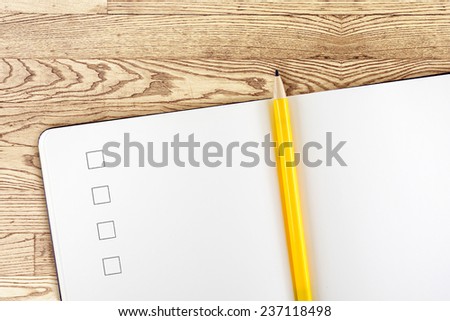 Open blank notebook with check box and yellow pencil on detail wooden table,Template mock up for adding your content