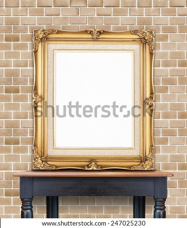 Blank vintage golden photo frame lean at pale orange brick  wall on wood table,Template Mock up for add picture.