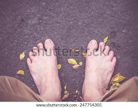 vintage filter: bare foot on black stone and dried leaves