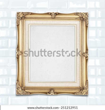 Blank Gold color vintage photo frame hanging on white ceramic tile wall,template for adding your photo
