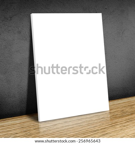 Blank white poster frame at wooden floor and black concrete wall, Canvas frame template Business concept