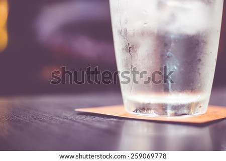 Vintage filter : Cold glass of water on wooden table at restaurant.