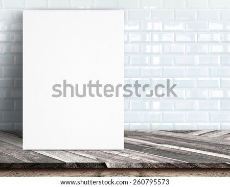 Black White paper poster lean at white ceramic tile wall and tropical wood table,Template mock up for adding your text.
