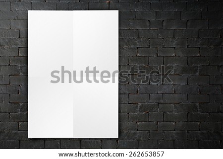 Blank folded paper poster hanging on black brick wall,Template mock up for adding your design.