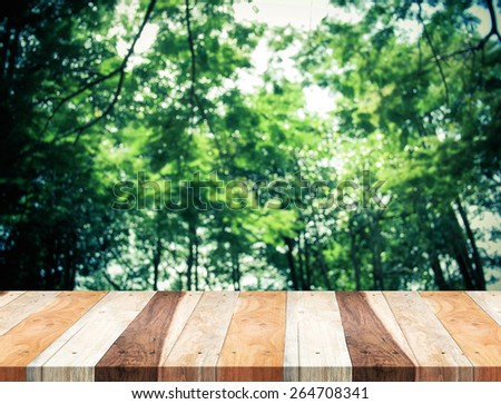 Empty perspective tropical wood table with blurred green tree forest,Template mock up for display of your product.