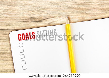 Goals Setting word on notebook lay on wood table,Template mock up for adding your goal.