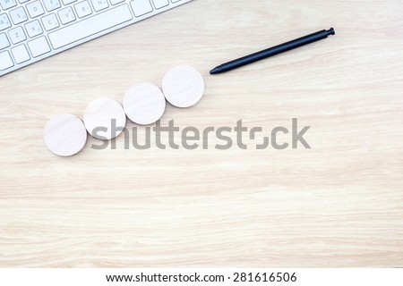 Black pen pointing at four piece of round wood with keyboard on wooden table , Mock up for adding your design