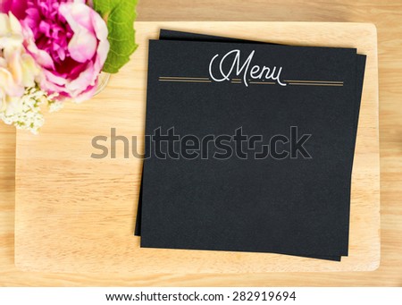 Top view of Blank wooden plate with black menu card and flower pot on table top,Mock up for adding your design, Clipping path on paper card.