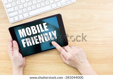 Finger click screen with Mobile friendly word with keyboard on wooden table,Responsive web design