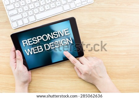 Finger click screen with Responsive web design word with keyboard on wooden table,Website design concept