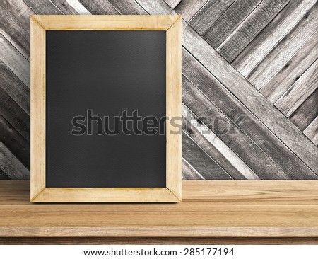 Blank blackboard wood frame on wooden table at diagonal wood wall,Template mock up for adding your design and leave space beside frame for adding more text.