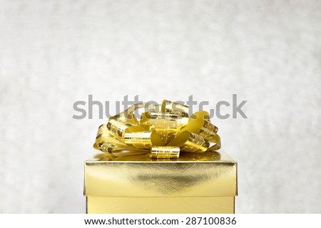 Golden present box with big bow at bokeh white blur background, Leave space to adding your content
