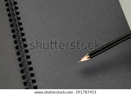 Close up at black pencil on blank black notebook,mock up for adding your content.