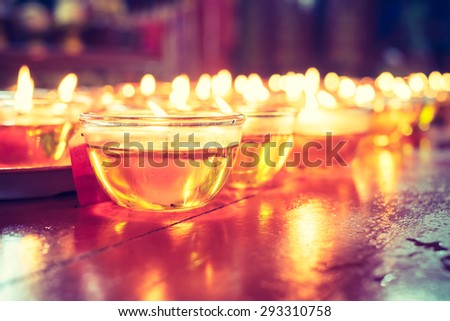 Pray candle glass on wood table in chinese temple.