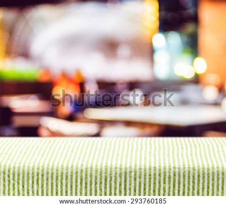Table with green pattern tablecloth with restaurant blur background, Mock up for display of product