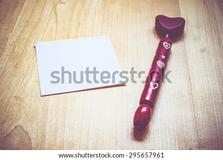 Vintage filter ,Blank Note paper and red heart shape pen on wood table,Template for you content