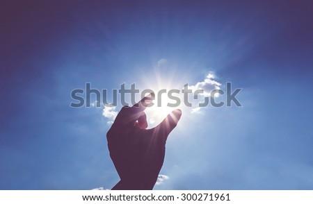 Vintage filter : Silhouette Hand picking sun with sun burst at blue sky, Business success concept