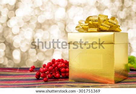 Gold present box with ribbon on table with sparkling gold bokeh light background, Leave space for adding your text