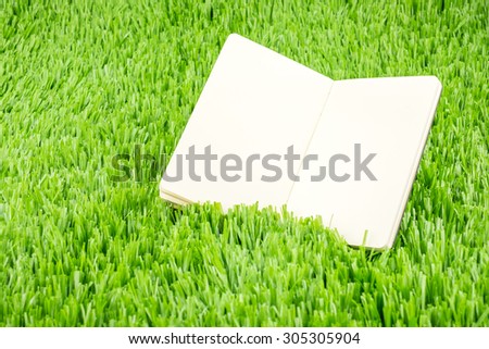 Open notebook on green grass, Business and Education concept template.
