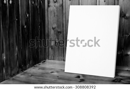 Blank white poster leaning at black and white wooden wall in plank wood room,Mock up for adding your content.