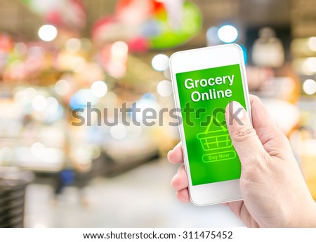 Hand holding mobile with grocery online on screen with blur supermarket background, Online delivery concept.