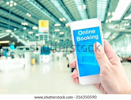 Hand holding mobile with online booking with blur airport background, Digital Booking concept