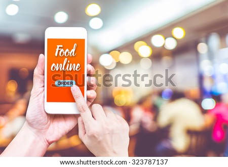 Hand holding mobile with Order food online with blur restaurant background, food online business concept.Leave space for adding your text